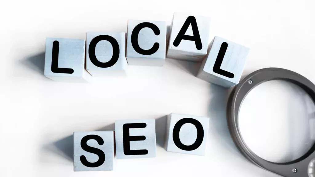 Wooden blocks spelling "LOCAL SEO" next to a magnifying glass, representing the importance of optimizing for Local SEO for service businesses.