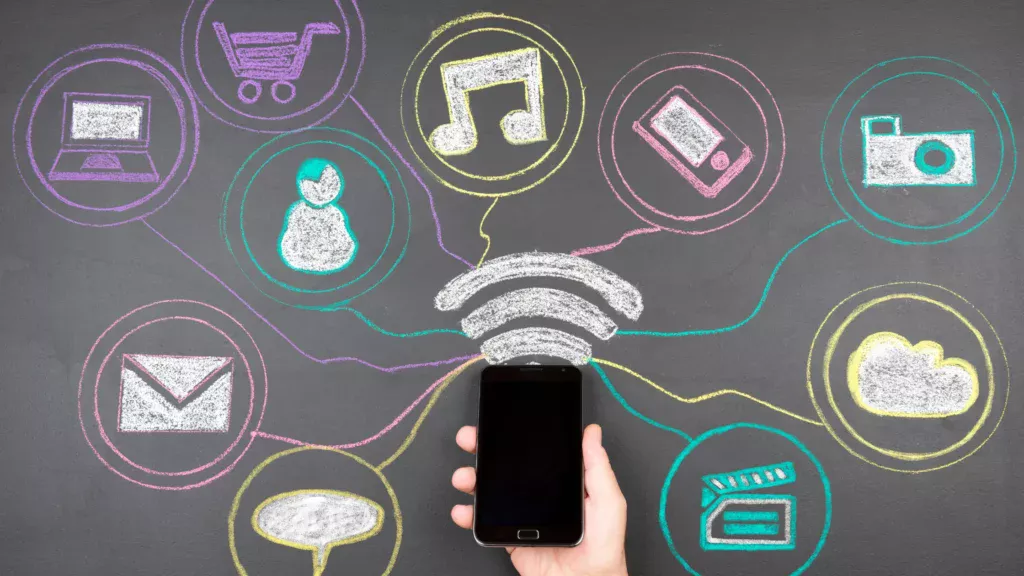 A hand holding a smartphone surrounded by various social media icons, highlighting social media marketing for small businesses.