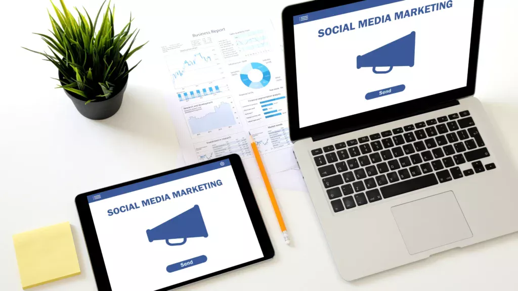 A tablet and laptop showing "SOCIAL MEDIA MARKETING" with graphs and business data, reflecting analytics in social media marketing for small businesses.